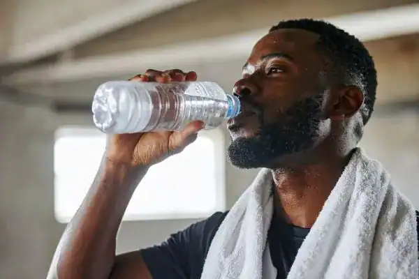 Image of man drinking water to improve hydration Cheshire after work out.
